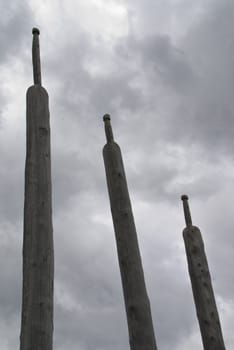 Three artfully shaped long stakes stand straight into the coming storm.