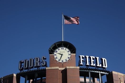 Facade clock and American flag over entrance to downtown Denver ballpark