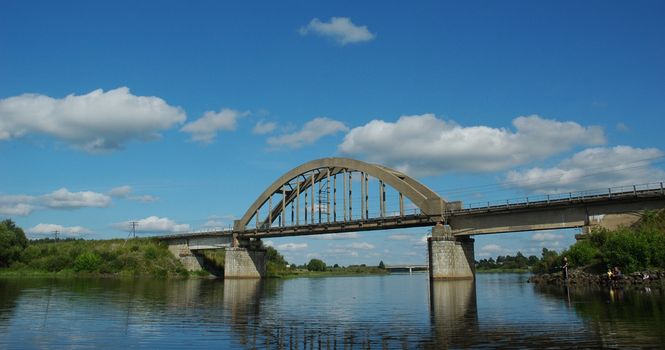 The railway bridge through small river on a background of the sky