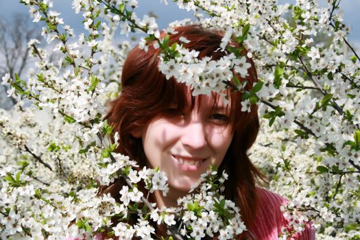 A beautiful girl enjoying the sunny weather in the middle of blooming cherry tree