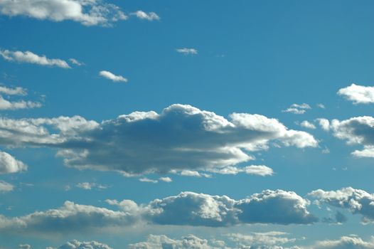 Bright blue sky with numerous clouds glowing with silver linings