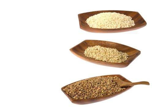 Lentils, white and brown rice on wooden trays isolated over white background.