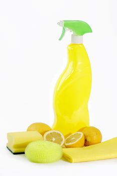 A yellow bottle of household cleaner spray with fresh lemons on bright background
