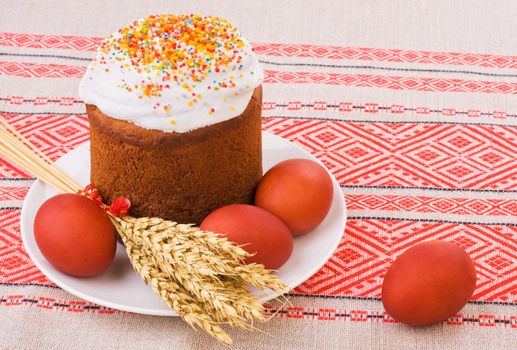 Easter Cake, Painted Eggs and Ears of Wheat on traditional tablecloth