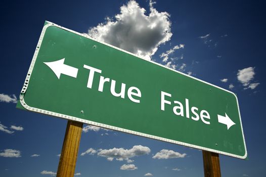 True, False road sign with dramatic blue sky and clouds.