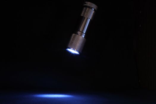 Modern little lighting electric torch hanging on dark background