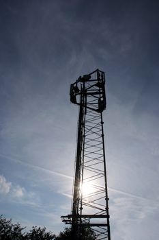 Telecommunication mast with a stormy sky background and the sun setting