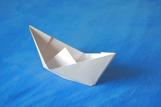 origami paper boat isolated on blue water