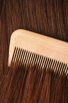 A comb running through long brown hair.
