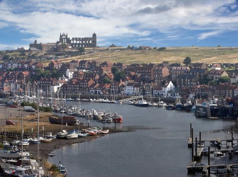 Whitby estuary harbour and town, with the ruined abbey on the hill above.