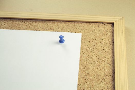 one piece of plain white notepaper on a cork board background