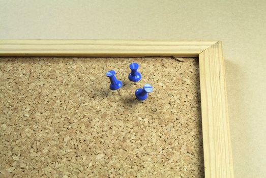 three pushpins on a cork notice board