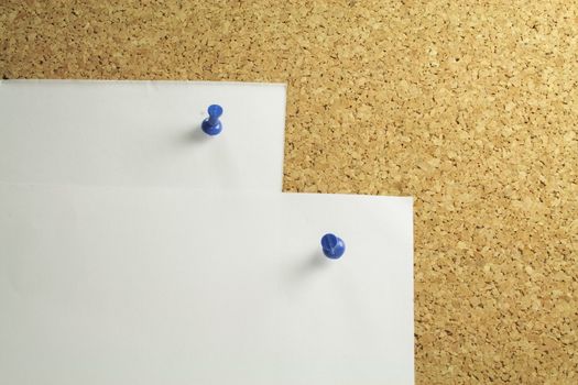 two pieces of white notepaper on a cork board background