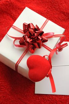 Gift box and fabric heart over red background