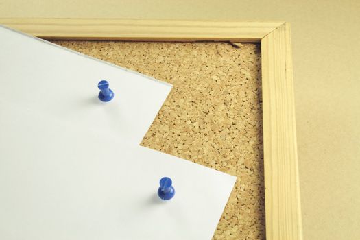 two pieces of white notepaper on a cork board background