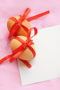 Easter greeting card of eggs and red ribbon over pink background