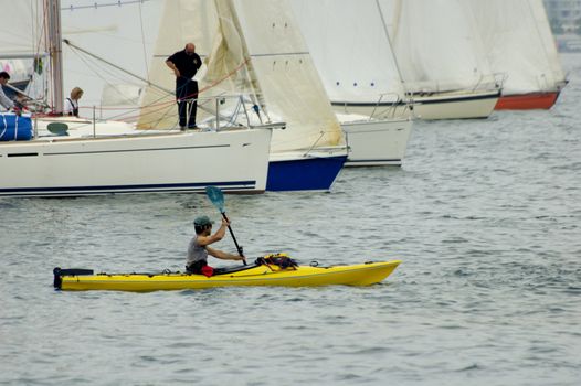 A canoeist seems to be taking 5 yachts on, for a race.