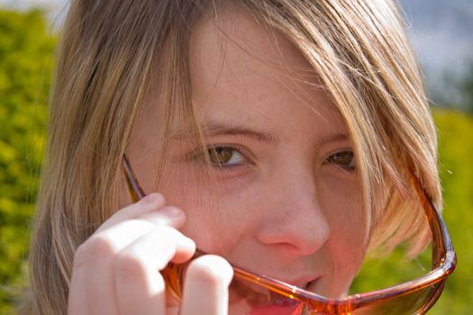 Pretty teenage girl looks at something over the top of her sunglasses.