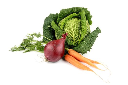Single green raw cabbage with a single red onion and a bunch of carrots on a reflective white background