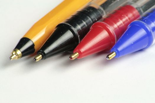 closeup of four different coloured ball point pens isolated over white