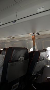 A hand pushing the help button on an airplane