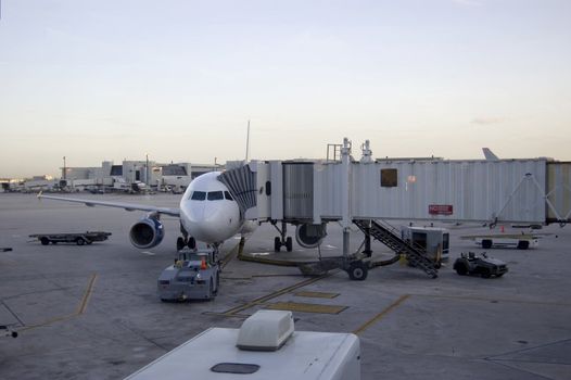 Airport Scene Showing airplane and different tractors and jet bridge
