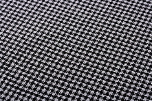 Fabric in a small black and white cage as a background for design works.