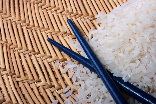 Rice on a straw mat with chopsticks.