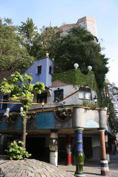 Hundertwasserhaus - famous extraordinary building in Vienna, Austria. Designed by Austrian artist Friedensreich Hundertwasser. Trees on roof.