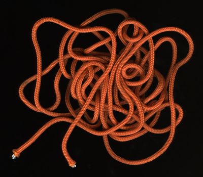 loose, random coils of orange, nylon cord against black background