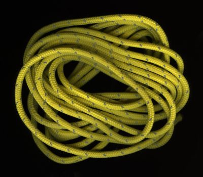loose coils of yellow, nylon rope wit a reflective, silver thread on black background