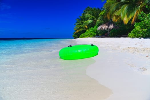 Green Swim Ring on empty beach at Maldives