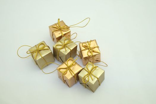 gold coloured  square boxed presents fastened with bows for hanging on the christmas tree