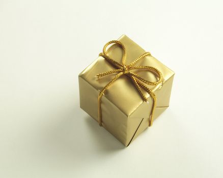 small golden wrapped present tied with gold string isolated over a white background