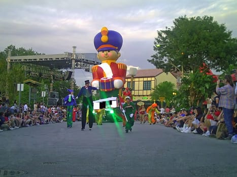 Crowds of people are enjoying themselves as they are watching the parade at one of the theme parks during Christmas.