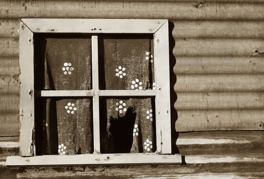 an old forlorn window with ripped and worn curtain in the wall of an iron house