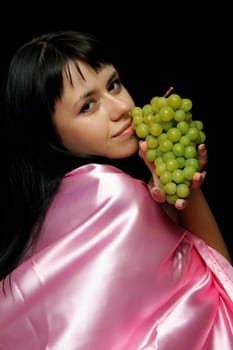Girl with a cluster of green grapes, isolated on black