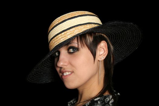 The young smiling girl in a straw hat, on a black background