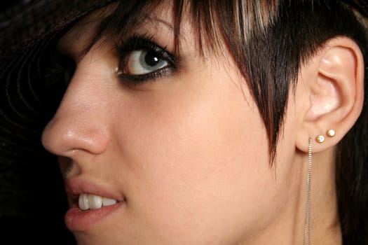 The young beautiful girl in a hat, on a black background