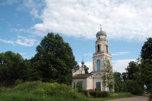 Rural orthodox church among greens on a background of the sky with clouds.