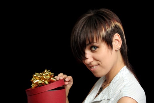 The young girl looks in a box with a gift, isolated on black background