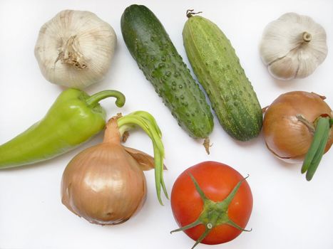 This is a photograph of some fresh and sweet vegetables: tomatoes, cucumbers, onions, garlic, peppers, radish. 