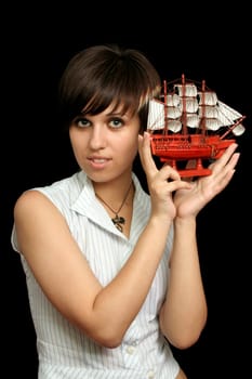 The nice girl with the toy ship in a hand, isolated on black background