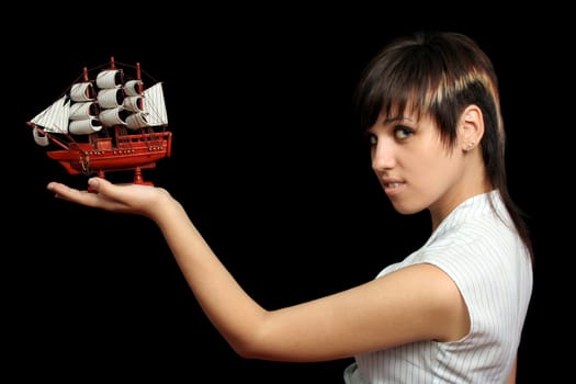 The nice girl with the toy ship in a hand, isolated on black background