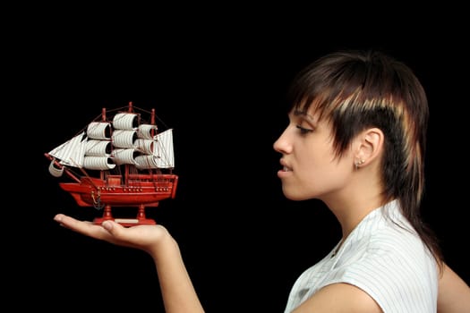 The nice smiling girl with the toy ship in a hand, isolated on black background