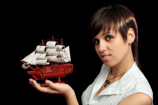 The nice smiling girl with the toy ship in a hand, isolated on black background