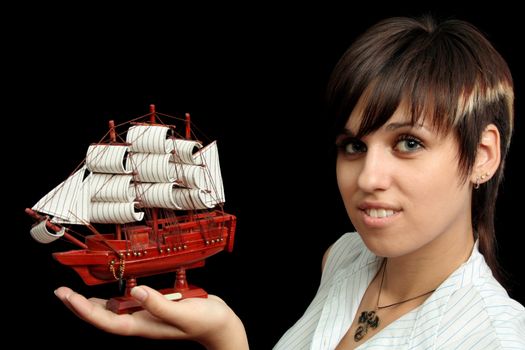 The nice smiling girl with the toy ship in a hand, isolated on black background