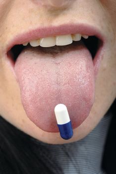 Blue pill in young woman's mouth