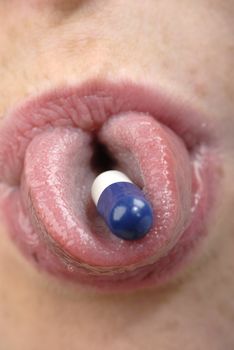 Young woman's  mouth with blue pill