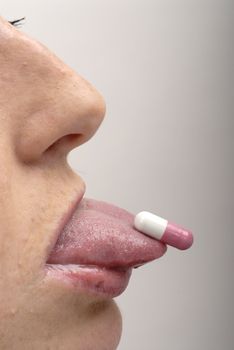 Young woman with pink pill on her tongue